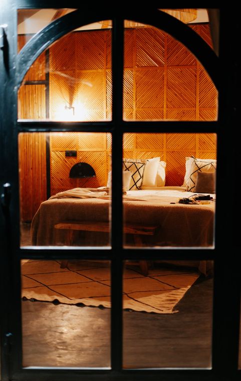 Lit bedroom seen through an arched glass door