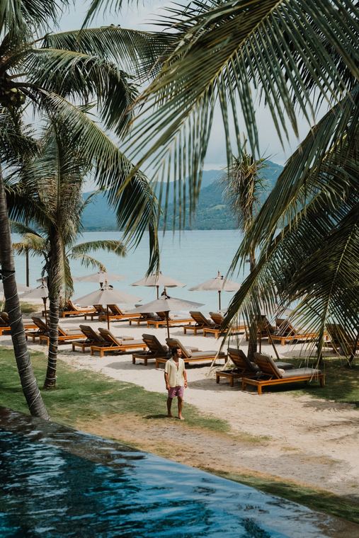 Walking between sun loungers and palms on the beach