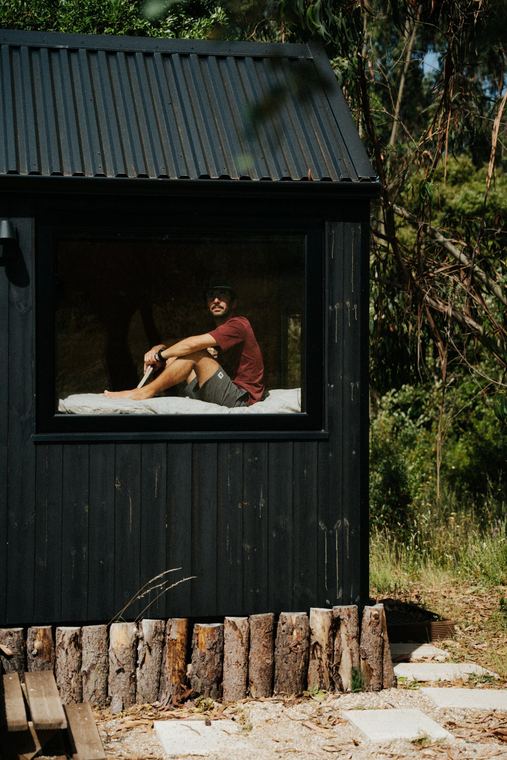 Sitting on the bed, seen through the window of the black cabin