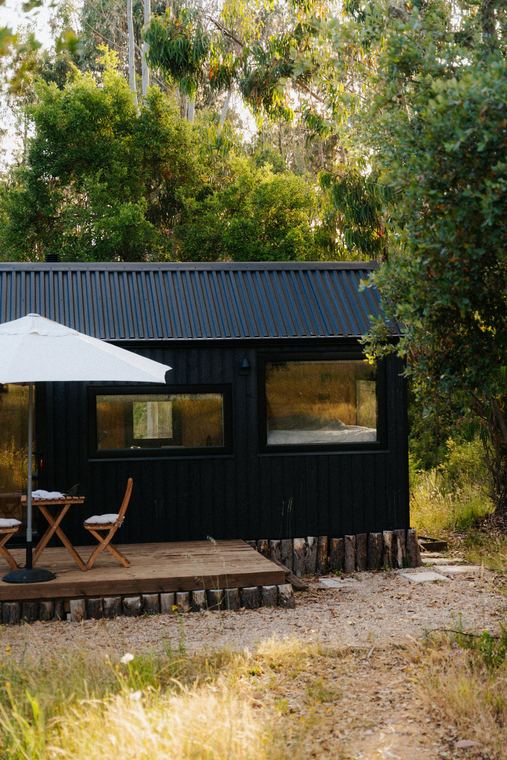 Black cabin with deck, table and parasol in golden light